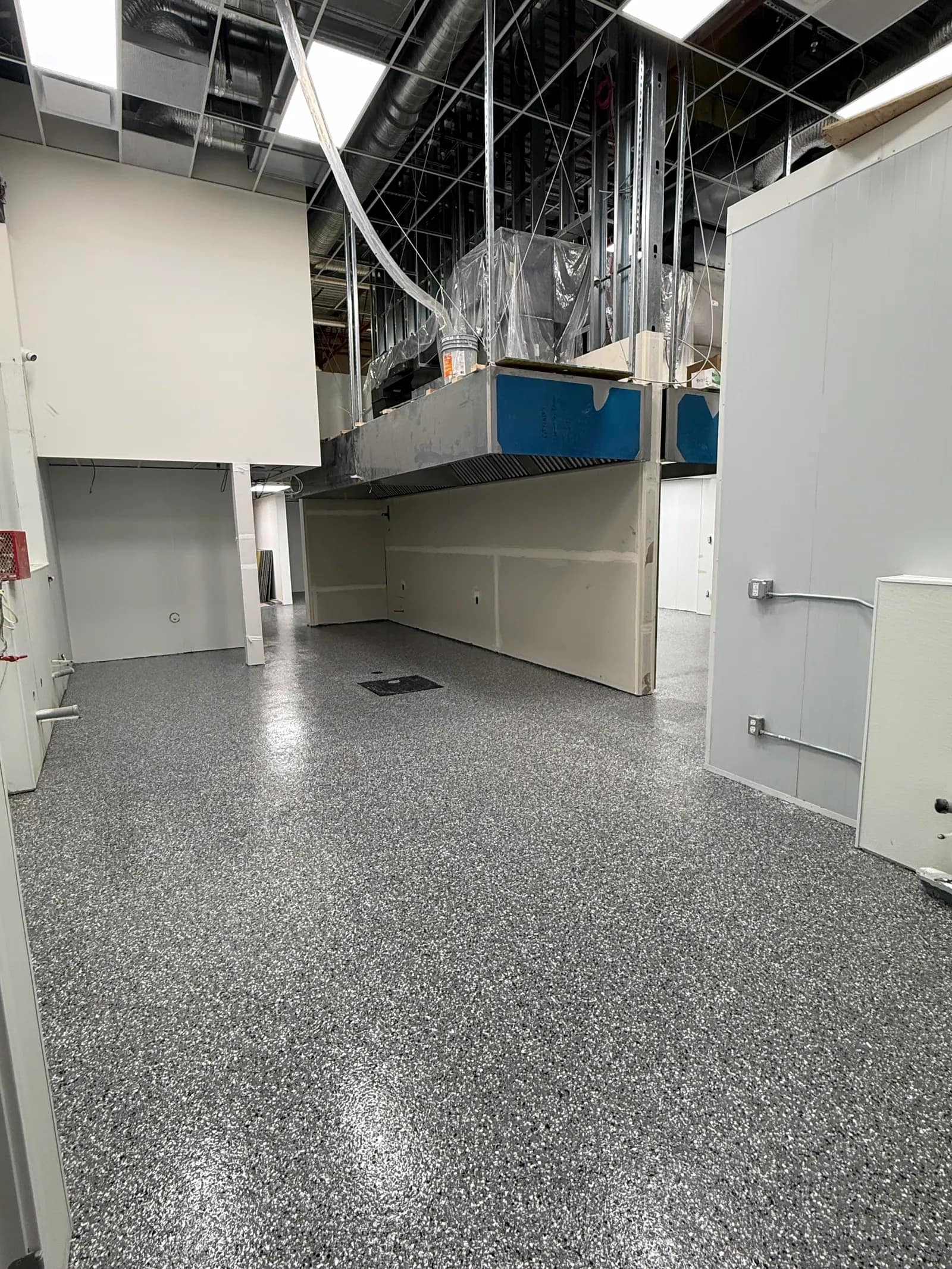 Back-of-house commercial space with a grey flake floor and a floor drain set flush into the slab