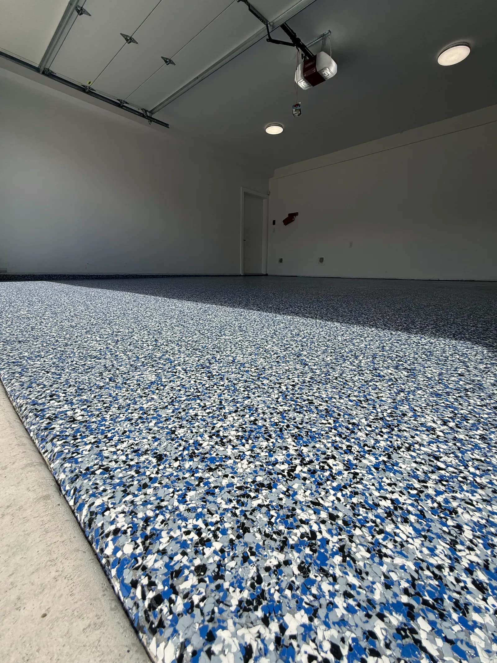 Garage floor in a blue, white and black flake blend, finished to a clean edge at the door opening
