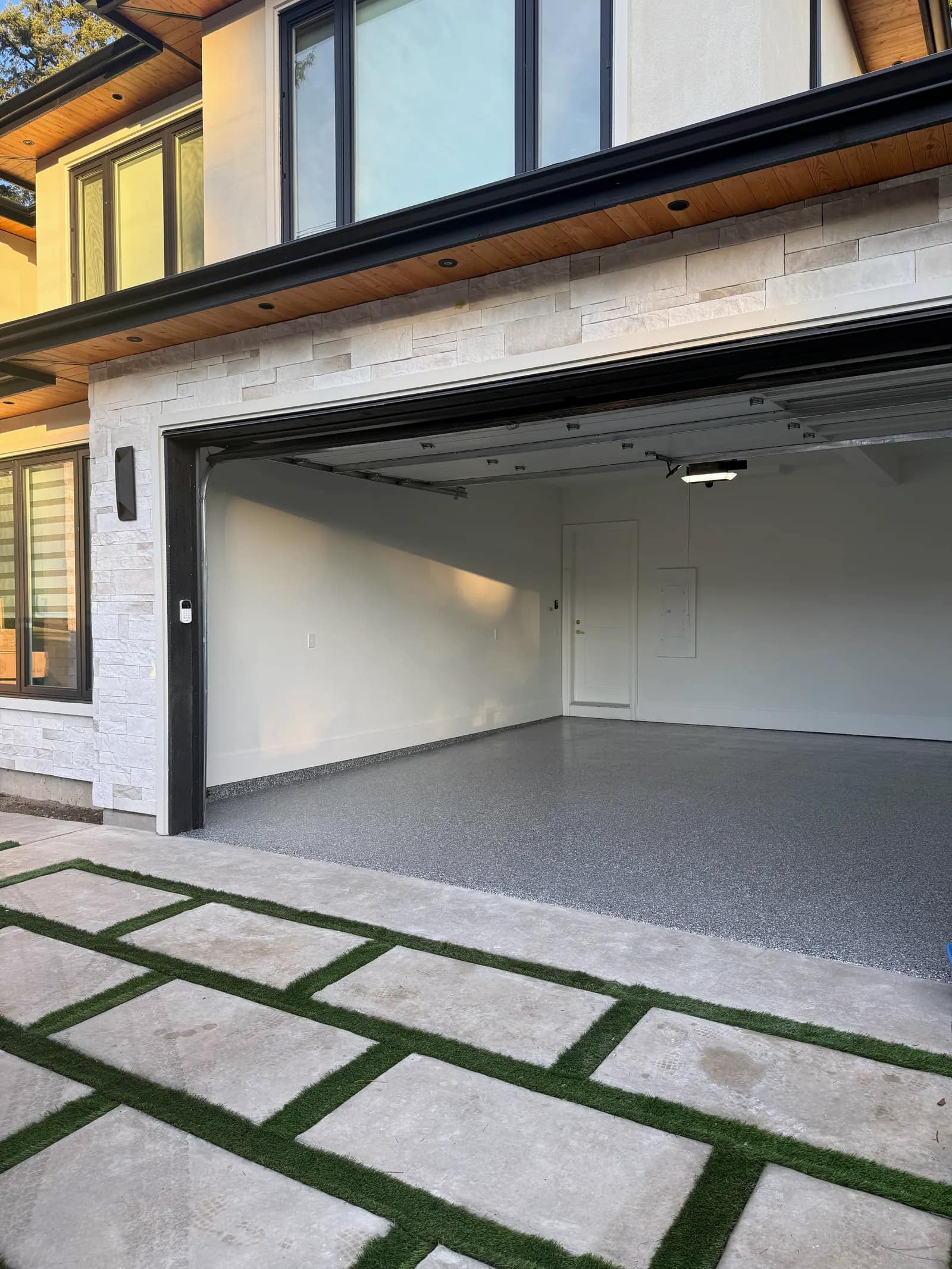 New build with the garage door open, showing a light grey flake epoxy floor running out to the slab edge