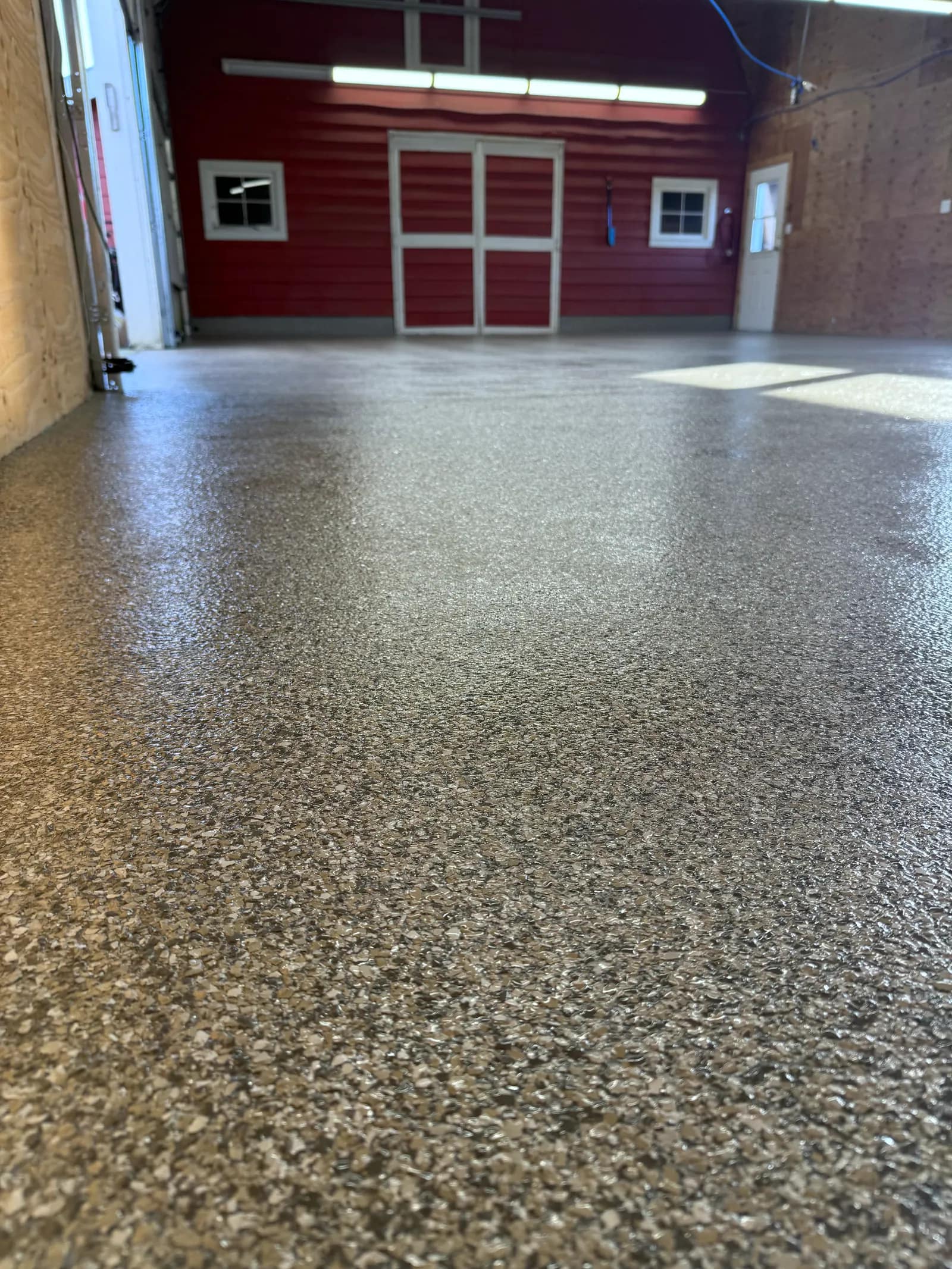 Shop interior with a tan and brown flake floor and a red painted end wall behind