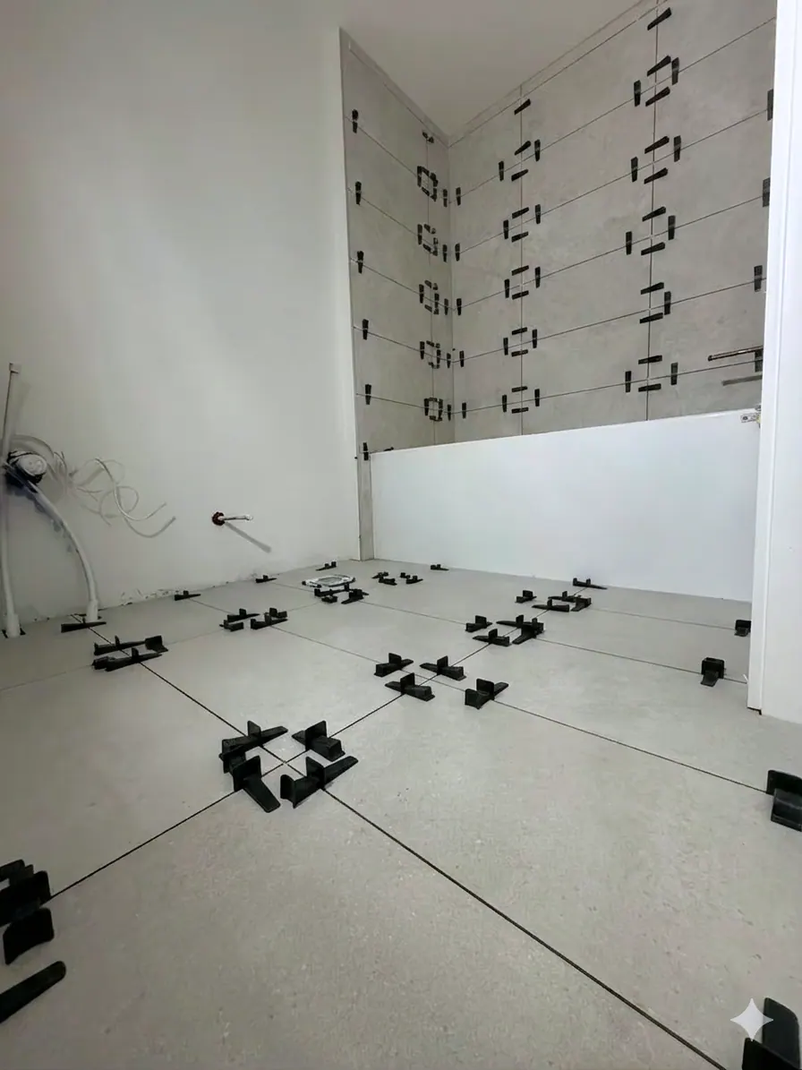 Bathroom tile installation in progress, with levelling clips set across large-format floor and wall tile